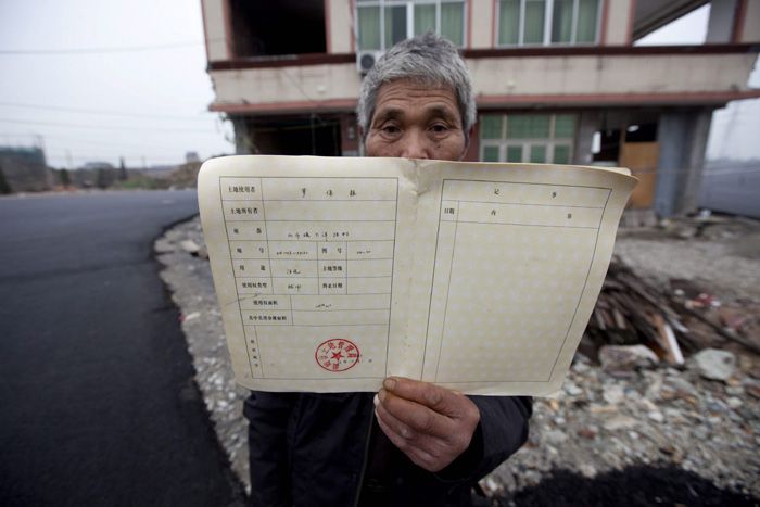 Luo Baogen, el dueño de una casa de cinco pisos, que permanece en medio de una avenida en construcción en la ciudad de Wenling (China). Luo muestra el certificado de propiedad del inmueble.