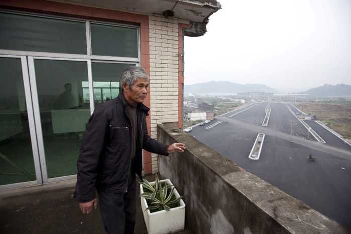 Luo Baogen, el dueño de una casa de cinco pisos que permanece en medio de una avenida en construcción en la ciudad de Wenling (China), asomándose en un balón del inmueble.